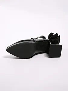Close-up of black chunky heel pumps featuring an oversized bow and anti-slip sole