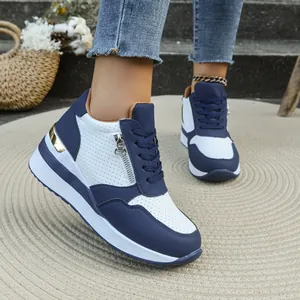 Dettaglio di sneaker con zeppa blu e bianche con cerniera laterale e fori traspiranti.