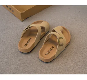 Dettaglio di sandali beige con fibbia per bambini su una superficie grigia.