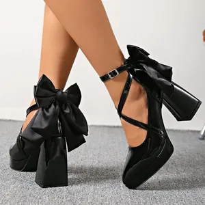 Elegant black chunky high heels with crossover straps and large satin bow detail on heel.