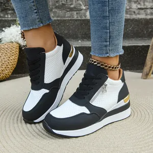 Dettaglio di sneaker con zeppa bianche e nere da donna con cerniera laterale e suola spessa