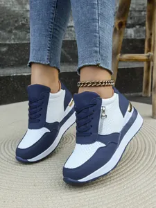 Dettaglio di sneaker con zeppa blu e bianche da donna con suola platform e cerniera laterale.