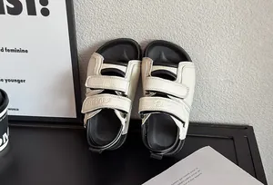 Gros plan de sandales crème pour enfants avec brides velcro et semelles noires