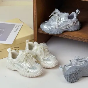 Vista dettagliata delle sneakers argento da bambina con perle e fiocchi in tulle.