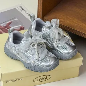 Dettaglio di sneakers argento da bambina con eleganti fiocchi in pizzo e perle