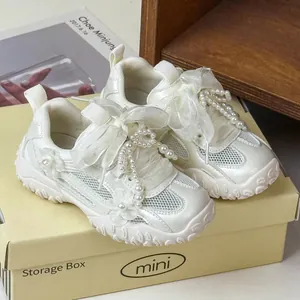 Dettaglio ravvicinato di sneaker in mesh bianco per bambina con perle e fiocco decorato