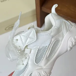 Dettaglio della scarpa sportiva argento da bambina con inserti in mesh e lacci a nastro
