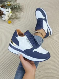 Dettaglio delle sneakers con zeppa blu e bianche con elegante accento dorato al tallone