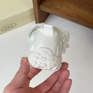 Dettaglio ravvicinato di sneaker bianche da principessa per bambine con perle e pizzo floreale