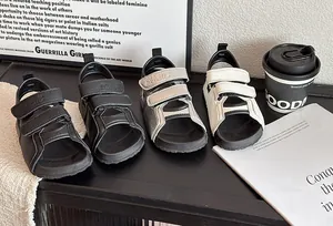 Détail de sandales pour enfants en noir, gris et blanc sur une table noire élégante
