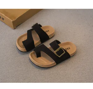 Sandali retrò per bambini con cinturini neri e fibbia in ottone su tappeto grigio chiaro