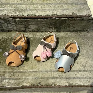 Detail view showing brown, pink, and silver girls tulip sandals on sunlit stone steps