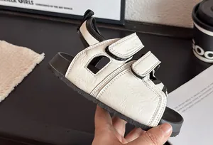 Détail rapproché de sandales d'été blanches pour enfants avec velcro et une semelle noire.