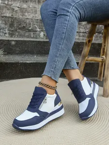 Dettaglio laterale di sneakers con zeppa da donna blu e bianche con lacci e cerniera laterale.