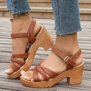 Women's brown chunky heel sandals with braided straps and ankle buckle on wooden deck.