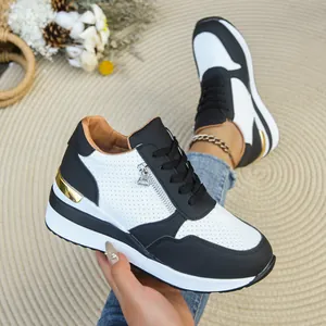 Dettaglio di sneaker zeppa bianche e nere da donna con cerniera laterale e suola platform.