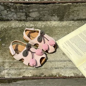 Detailed view of pink girls tulip sandals with soft soles on rustic concrete steps