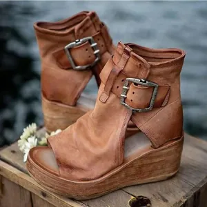 Nahaufnahme von braunen Vintage-Leder-Keilsandalen mit offener Spitze und großen Metallschnallen