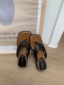 Gros plan sur des tongs noires à bout carré avec une semelle intérieure marron confortable