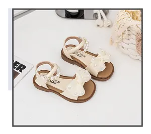 Detailansicht beige Mädchensandalen mit eleganten perlenbesetzten Schleifen und Riemen.