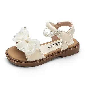 Elegante cremefarbene Mädchensandalen mit einer Perlenschleife und einem Perlenriemen