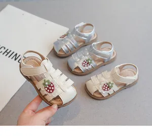 Detailed view of cream girls' sandals featuring strawberry charm and soft non-slip sole