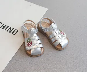 Detailed close-up of silver toddler girl sandals with strawberry decoration and closed toe