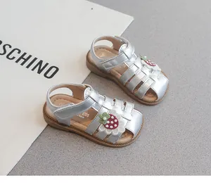 Close-up detail shot of silver baby girl sandals with strawberry patch and pearl accents.