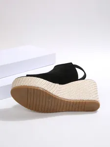 Detailansicht der schwarzen Keilsandalen für Damen mit geflochtenem Plateau und Gummisohle