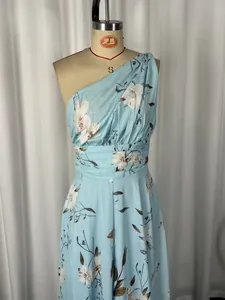 Détail d'une élégante robe longue à fleurs bleu clair à une épaule en mousseline.