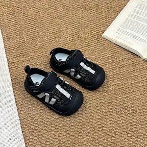 Gros plan de sandales en maille noire pour enfants avec rayures blanches sur un tapis