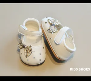Detalle de zapatos de marcha blancos para niña con lazo y diseño de flores caladas