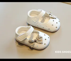 Detalle de zapatos blancos para niñas bebés con lazo de cuadros y patrones perforados