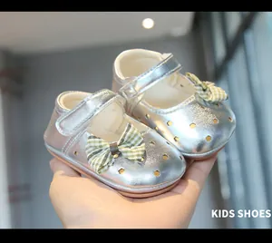 Detalle de zapatos plateados para bebé con calados de corazón y lazo. (80 chars)