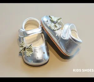 Primer plano de zapatos plateados para bebé niña con lazo verde y calados de estrellas