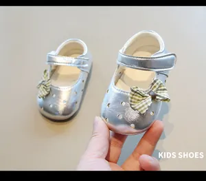 Primer plano de zapatos Mary Jane plateados para bebé con lazo y calados de estrella