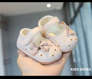 Primer plano de zapatos de cuero rosa para bebé niña con lazo y diseño calado