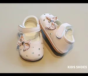 Detalle de zapatos rosa para bebé niña con calado de flores y lazo