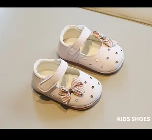 Detalle de zapatos rosa para bebé niña con lazo y calados de corazón.