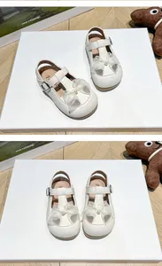 Close-up detail of cream toddler walking shoes featuring a delicate organza bow and pearl center