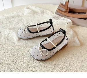 Gros plan de chaussures princesse en maille à pois blancs pour filles avec un nœud