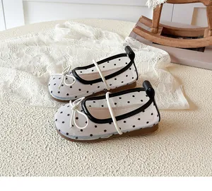 Détail de chaussures de princesse en maille blanche pour filles avec pois noirs