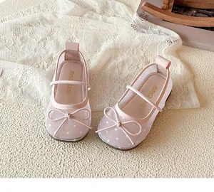 Gros plan de chaussures princesse en maille rose pour fille avec nœud et pois