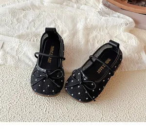 Détail de chaussures de princesse en maille à pois noirs pour filles avec nœuds décoratifs.