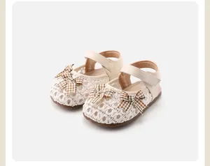 Nahaufnahme von gewebten Baby-Sandalen in Creme mit karierter Schleife und weicher Sohle