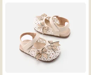 Detailaufnahme von cremefarbenen gewebten Babysandalen mit karierten Schleifen und weicher Sohle.