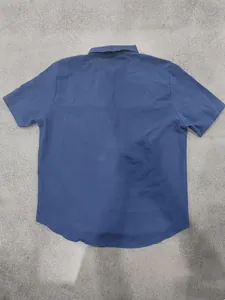Rear view of a classic blue casual short-sleeve shirt featuring a curved hem design