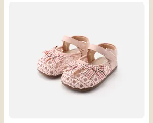 Detailansicht rosa geflochtener Babysandalen mit karierten Schleifen und Klettverschluss.