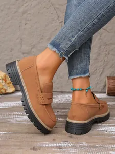 Detailed side view of stylish brown suede platform loafers with rugged thick soles.