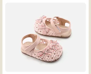 Detail von rosa gewebten Babysandalen für Mädchen mit karierter Schleife und weicher Sohle.